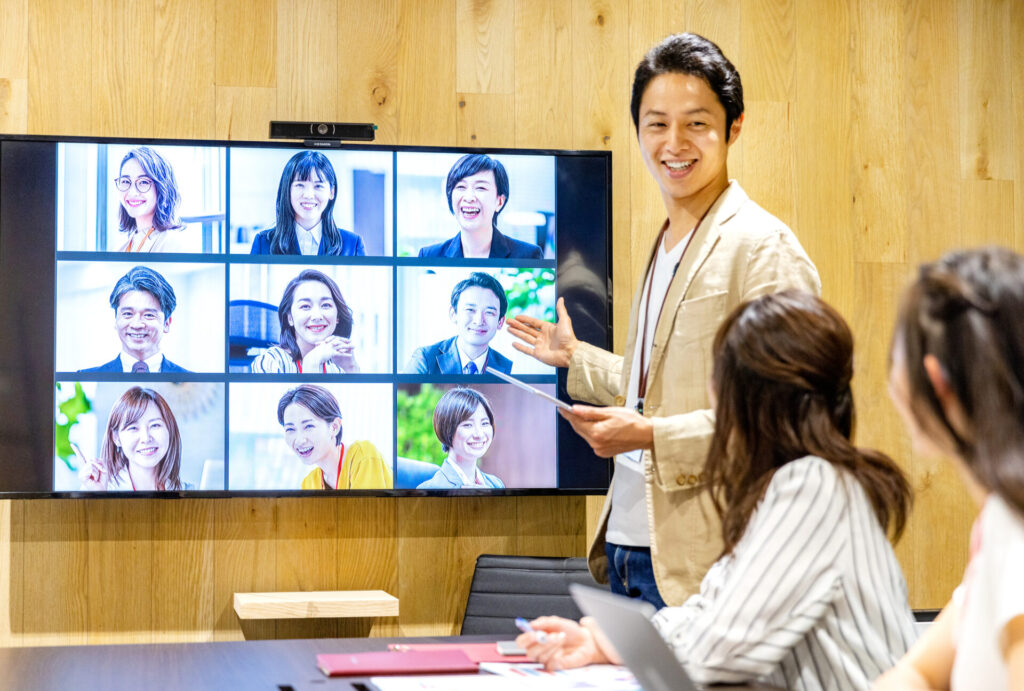 オフィス勤務とリモートワークのハイブリッドワークで会議をする従業員