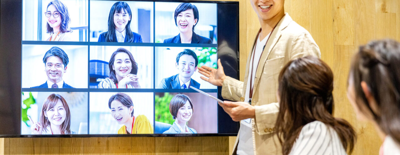 オフィス勤務とリモートワークのハイブリッドワークで会議をする従業員